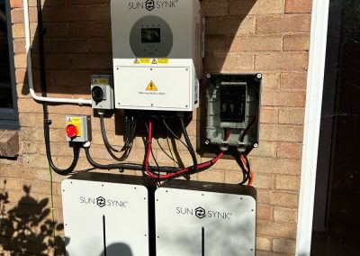 sunsynk inverter and batteries on a brick house wall
